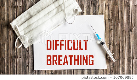 Difficulty breathing - the word is written on a white piece of paper and a wooden board.  107069895