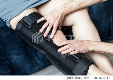 Rehabilitation concept. Man therapist and knee brace in physiotherapy with woman patient, knee pain  107070012