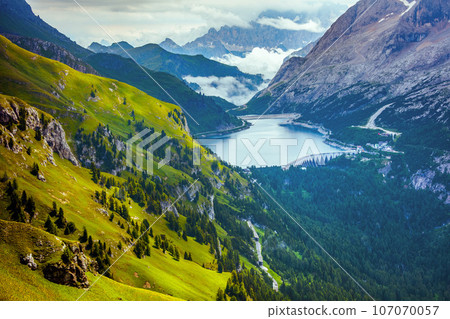 landscape with mountains, hills, Fedaia lake, clouds and trees 107070057