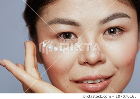 modern woman with eye cream on face 107070163