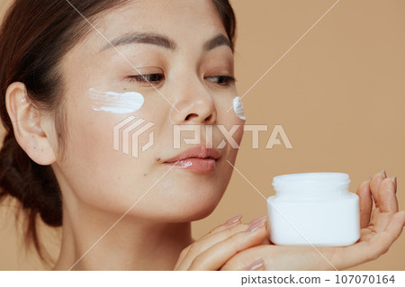 modern asian woman with facial cream jar 107070164