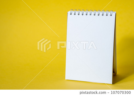 Opened notepad on a yellow background. Composition of writing to-dos for the day. The notebook lies on a plain background with space for writing. Opened notepad on a yellow background. Composition of writing to-dos for the day. The notebook lies on a plain background with space for writing. 107070300