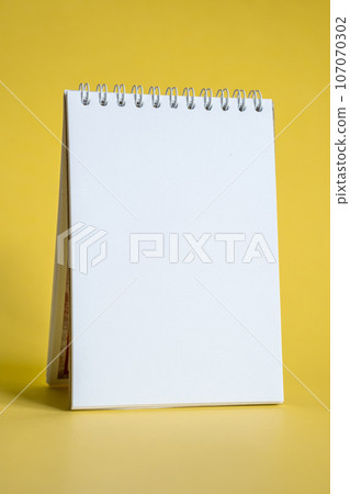 Opened notepad on a yellow background. Composition of writing to-dos for the day. The notebook lies on a plain background with space for writing.  107070302