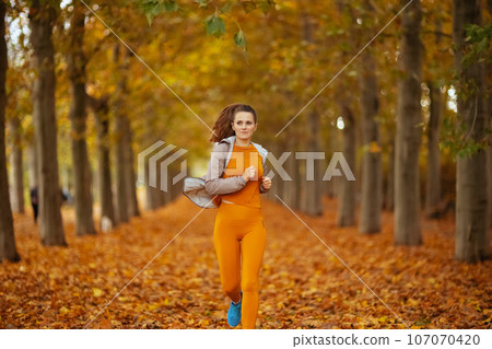 stylish female in fitness clothes in park jogging stylish female in fitness clothes in park jogging 107070420