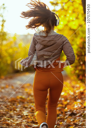 stylish female in park listening to music and running 107070430