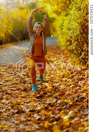 young female in fitness clothes in park stretching 107070431