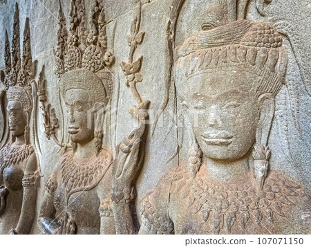 The famous bas-relief of Apsaras, celestial maidens, with intricate hairstyles on the inside wall of the first floor of the Angkor Wat temple in Siem Reap, Cambodia. The famous bas-relief of Apsaras, celestial maidens, with intricate hairstyles on the inside wall of the first floor of the Angkor Wat temple in Siem Reap, Cambodia. 107071150