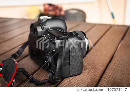 Camera Canon on wooden table. Photography hobby. Modern media technology. Digital optical camera. Professional body cam. Entertainment concept.  107071447