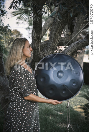 Portrait of a woman with a handpan her hands 107072070