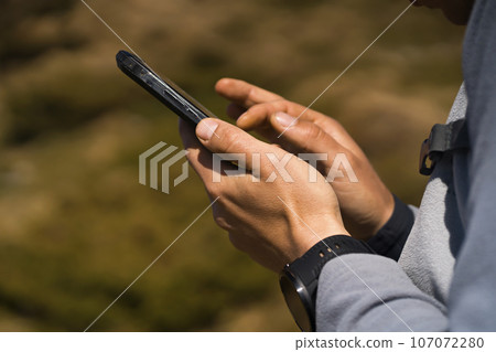 Man holds a smartphone in his hands and looks at a map, 107072280