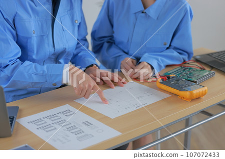 Male and female engineers_Hand checking block diagram 1 107072433