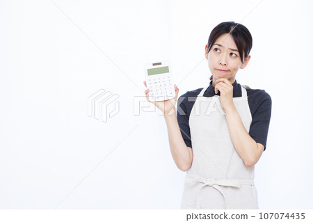 一位 30 多歲的陷入困境的家庭主婦在白色背景前拿著計算器 107074435