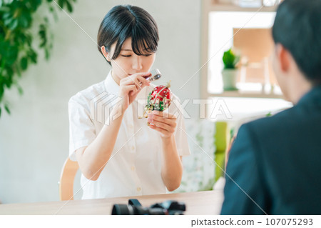 A young female staff member appraises antiques during a purchasing visit. 107075293