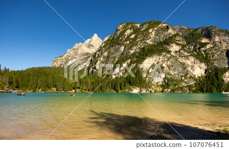 Alpine lake Braies amidst rocky peaks of Dolomite mountains, Italy 107076451