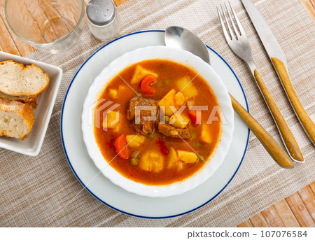 Delicious stewed pork in sauce with potatoes and vegetables. Traditional spanish dish patatas estofadas con carne 107076584