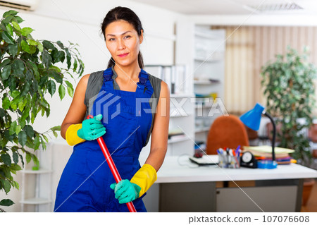 Woman wiping office floor with mop Woman wiping office floor with mop 107076608