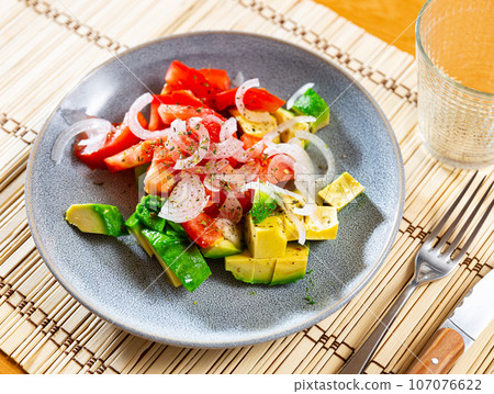 Salad from ripe avocado with tomatoes and onions 107076622