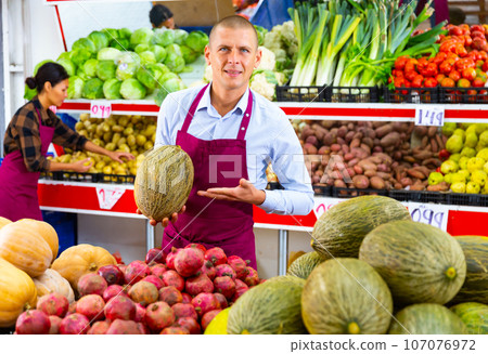 Man in apron standing in greengrocer Man in apron standing in greengrocer 107076972