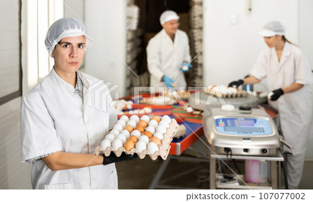 Latino woman holding carton tray with fresh eggs 107077002