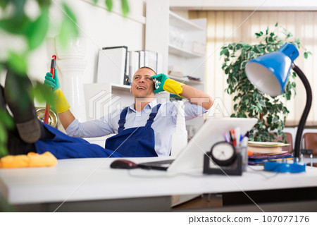 Relaxed worker of office cleaning service talking on phone during break 107077176