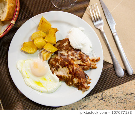 Traditional spanish fried pork with potato and egg on plate. Cerdo patata eggs Traditional spanish fried pork with potato and egg on plate. Cerdo patata eggs 107077188