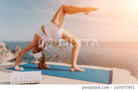 Fitness woman sea. Outdoor workout on yoga mat roller in park near to ocean beach. Female fitness pilates yoga routine concept. Healthy lifestyle. Happy fit woman exercising with rubber band in park. Fitness woman sea. Outdoor workout on yoga mat roller in park near to ocean beach. Female fitness pilates yoga routine concept. Healthy lifestyle. Happy fit woman exercising with rubber band in park. 107077951