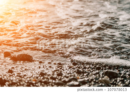 Blurred golden sea at sunset. The sun reflects and sparkles on the waves with bokeh, illuminating the golden sea. Holiday recreation concept. Abstract nautical summer ocean sunset nature background. Blurred golden sea at sunset. The sun reflects and sparkles on the waves with bokeh, illuminating the golden sea. Holiday recreation concept. Abstract nautical summer ocean sunset nature background. 107078013