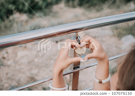 Hands, lock, heart, love, valentines day. Close-up of a woman's hands holding heart shaped padlock with a heart. The concept of Valentine's day, wedding, symbol of love and fidelity. 107078130