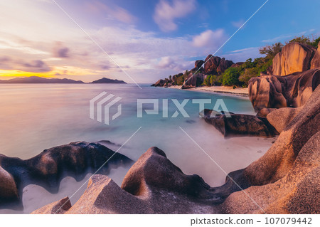 Beautifully shaped granite boulders and a dramatic sunset at picture perfect tropical Anse Source d'Argent beach, La Digue island, Seychelles. Beautifully shaped granite boulders and a dramatic sunset at picture perfect tropical Anse Source d'Argent beach, La Digue island, Seychelles. 107079442