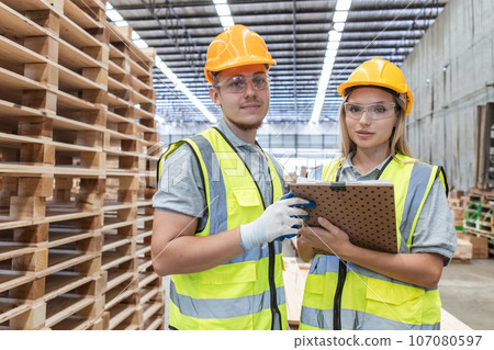 Team engineer carpenter wearing safety uniform and hard hat working holding clipboard checking. 107080597