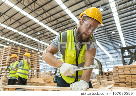 Male engineer carpenter wearing safety uniform and yellow hard hat working using hammer nail Male engineer carpenter wearing safety uniform and yellow hard hat working using hammer nail 107080599