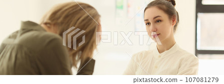 Female manager looks at sad employee while sitting at office desk. Female manager looks at sad employee while sitting at office desk. 107081279