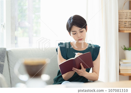 A woman looking at a notebook in the living room A woman looking at a notebook in the living room 107081310