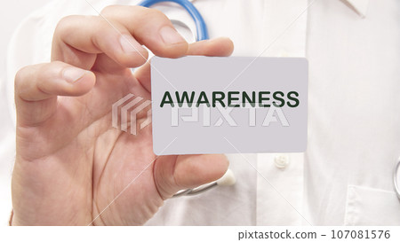 AWARENESS word on the card in a man's hand on the background of a white shirt 107081576