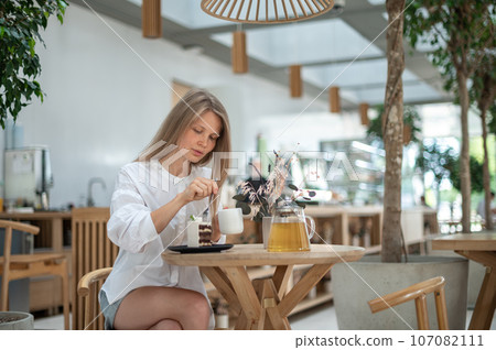 Girl in cafe eat cake with tea 107082111