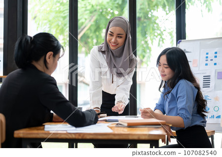 A beautiful Asian Muslim female leader is listening to her team's ideas in the meeting. 107082540