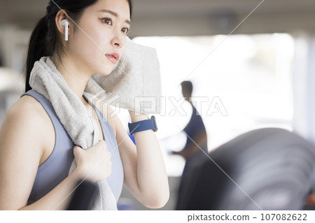 戴著無線耳機在健身房擦汗的年輕女子 107082622