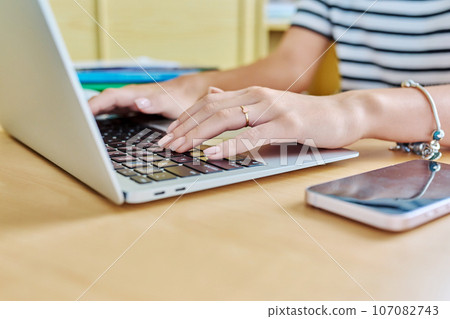 Close up of hands of young female student typing on laptop 107082743