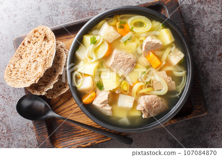 Kottsoppa soup is a meat and root vegetables include carrot, potato, celeriac, parsnip, turnip and Rutabaga close-up on a plate. Horizontal top view 107084870