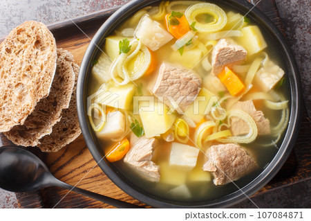 Aromatic root vegetable soup with beef served with rye bread close-up in a bowl. Horizontal top view Aromatic root vegetable soup with beef served with rye bread close-up in a bowl. Horizontal top view 107084871