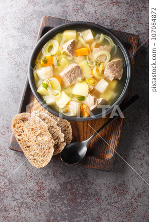 Finnish and Swedish Kottsoppa soup with beef, potatoes, carrots, leeks, celery and parsnip close-up in a plate. Vertical top view 107084872