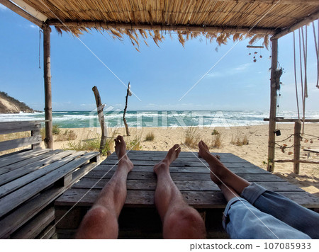 Legs of a couple on a beach table Legs of a couple on a beach table 107085933