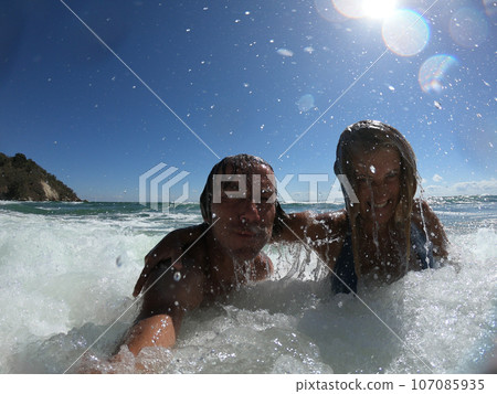Powerful ocean waves splashing funny couple Powerful ocean waves splashing funny couple 107085935