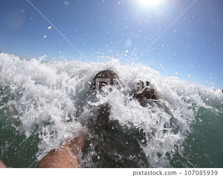 Ocean waves splashing on a romantic couple Ocean waves splashing on a romantic couple 107085939