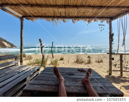 Legs of a relaxing guy on a beach table Legs of a relaxing guy on a beach table 107085955
