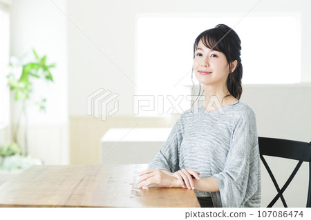 Young woman sitting at a table in the living room Young woman sitting at a table in the living room 107086474