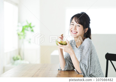 Young woman eating salad in the living room Young woman eating salad in the living room 107086482