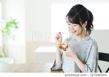 Young woman eating dessert in the living room Young woman eating dessert in the living room 107086484