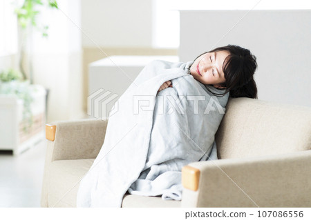客廳沙發上穿著毯子的年輕女人 107086556
