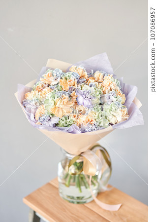 Beautiful bouquet of fresh flowers in glass vase on wooden table. A gift bouquet in mix color scheme for any holiday. The concept of a small flower shop. Flower and gift delivery 107086957